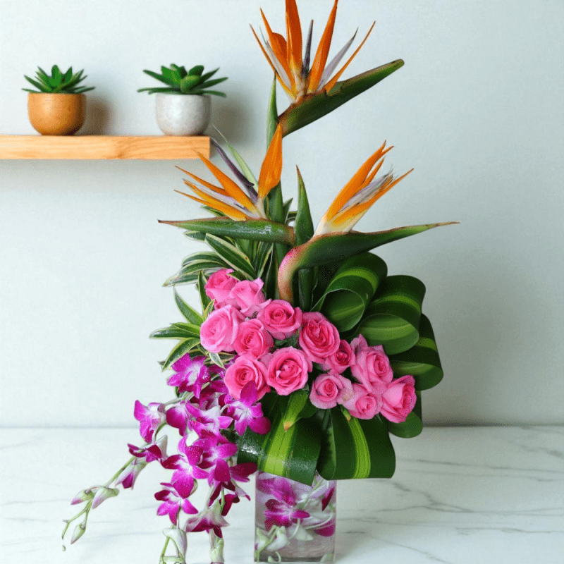 Exotic Flower Vase Arrangement – Pink roses, orchids & Bird of Paradise in designer vase with tropical leaves.
