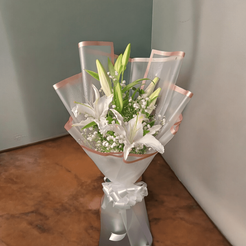 White lily flower bouquet wrapped in elegant paper with ribbon bow